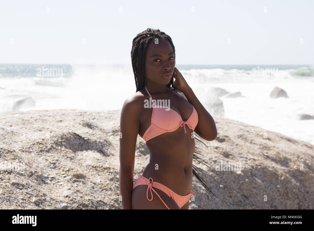 Portrait von wunderschönen afrikanischen Bikini Model mit Zöpfe in die Kamera schaut mit dem Strand im Hintergrund Stockfoto