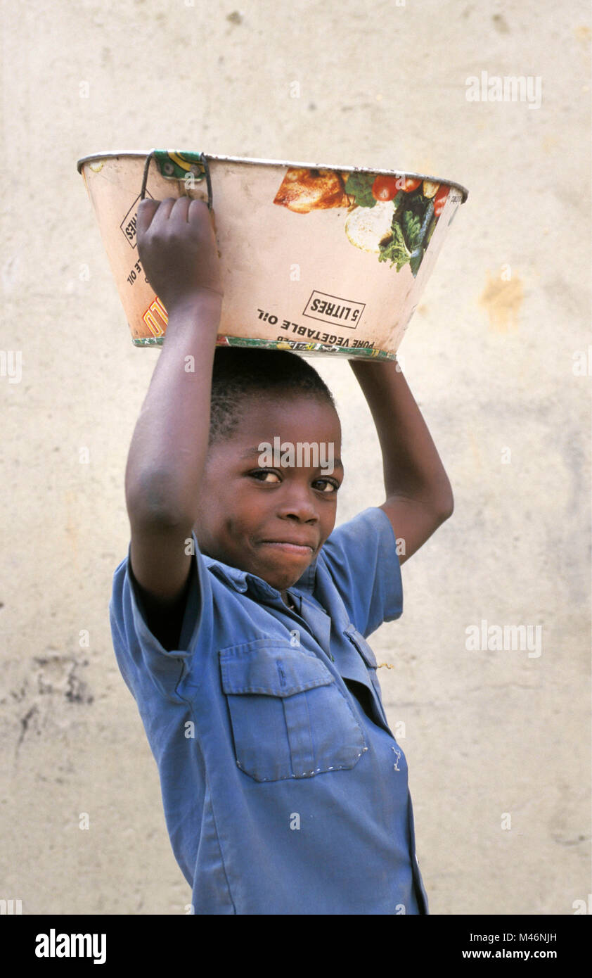 Simbabwe. In der Nähe von Harare. Junge die Schüssel auf den Kopf. Stockfoto