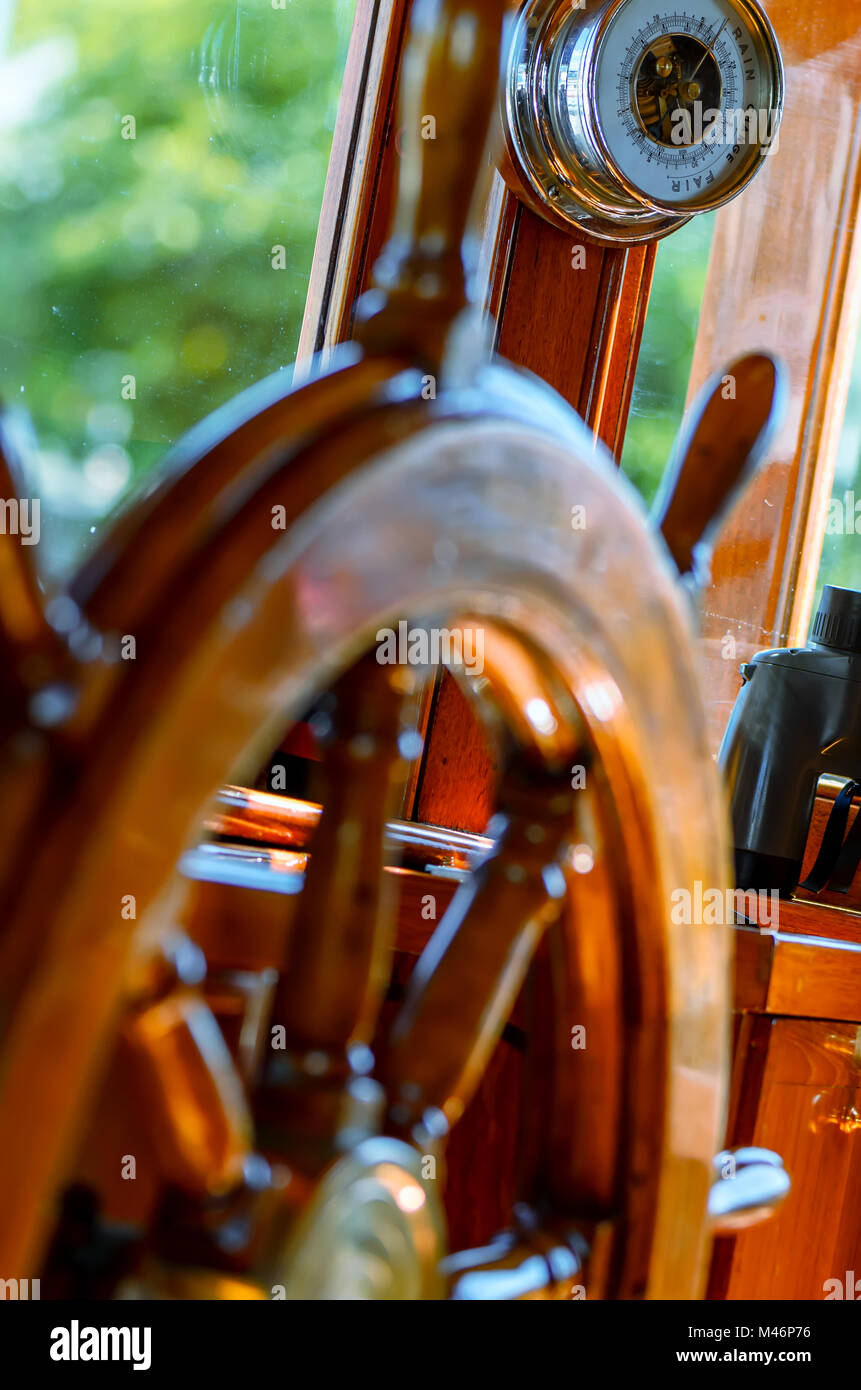 Rot, Alte, lackiert, Holz- Lenkrad auf einer Marine Yacht close-up, Barometer und Ferngläser im Hintergrund Stockfoto