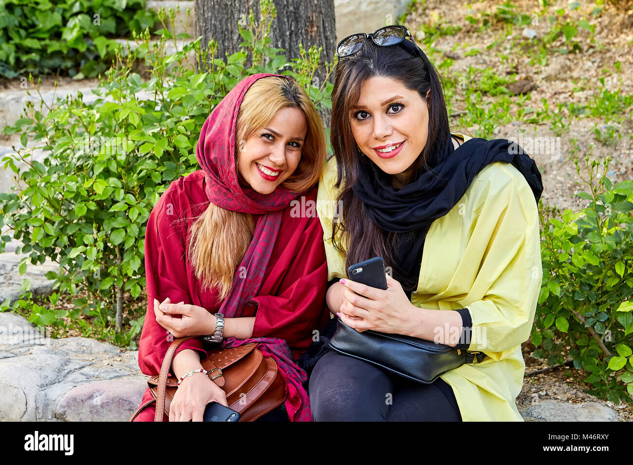 Teheran, Iran - 28. April 2017: zwei iranische Frauen in religiösen Schleier Sitzen im Park und lächelnd. Stockfoto