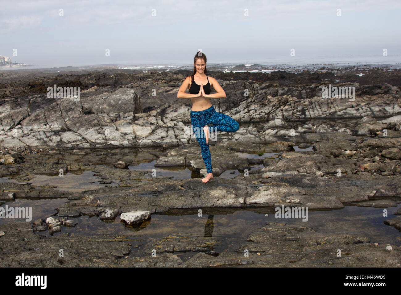 Eine attraktive weibliche Yoga am Strand und lächelnd in die Kamera Stockfoto