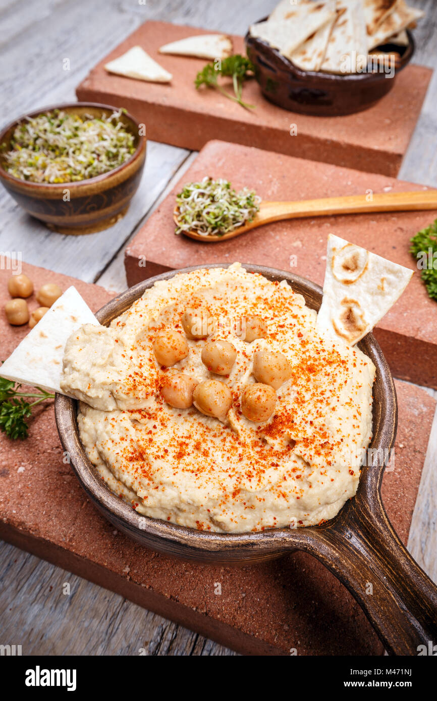 Hummus serviert mit frischem Fladenbrot und sprießen, gewürzt mit Paprika in vintage Keramikplatte Stockfoto