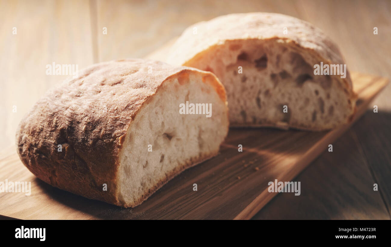 Hälften des frischen Ciabatta auf Oliven Schneidebrett Stockfoto