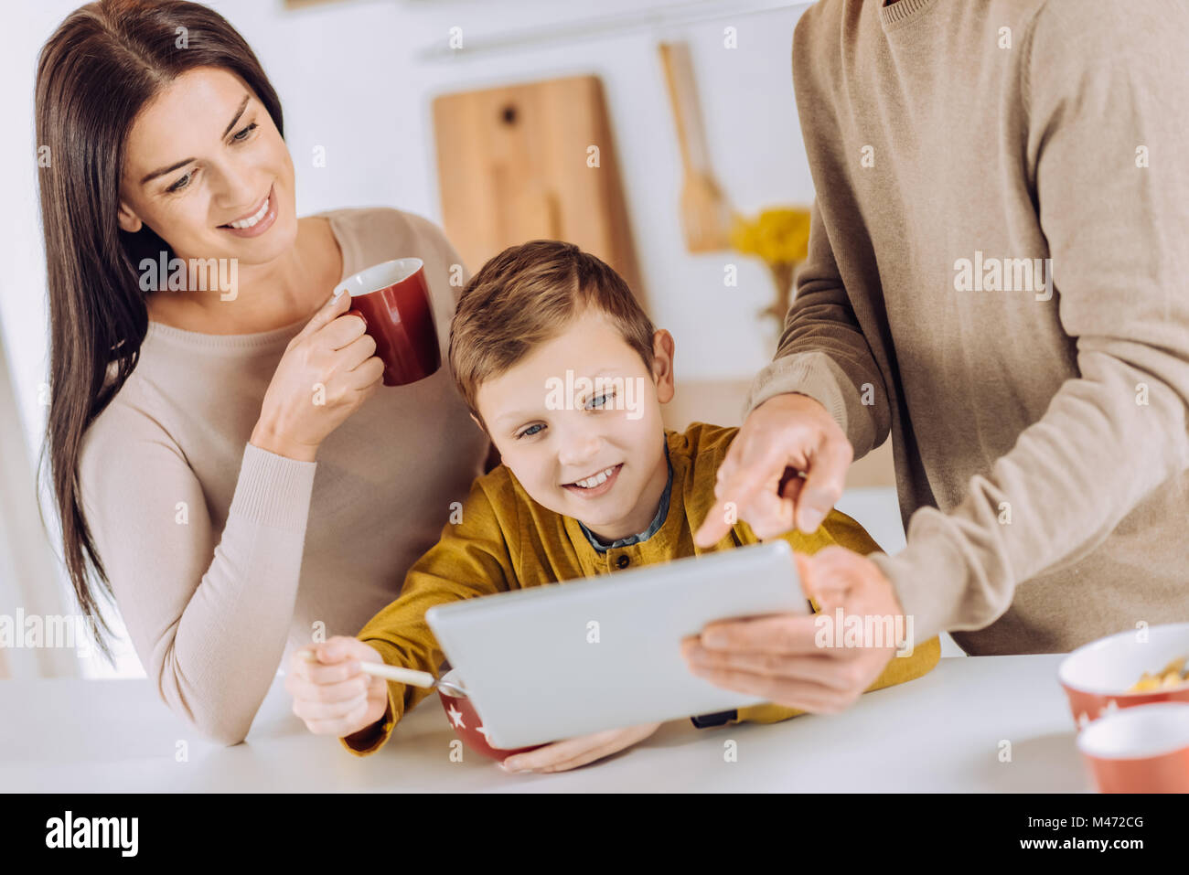 Angenehme Eltern zeigen Video zum Sohn, während er das Essen Stockfoto