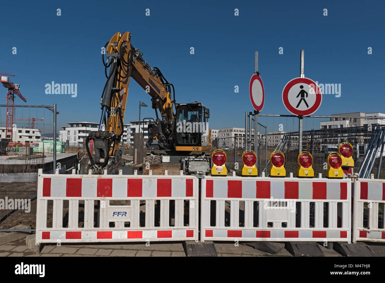 Gelber Radlader hinter einer geschlossenen Baustelle Eingang in den neuen Stadtteil Riedberg, Frankfurt, Deutschland Stockfoto