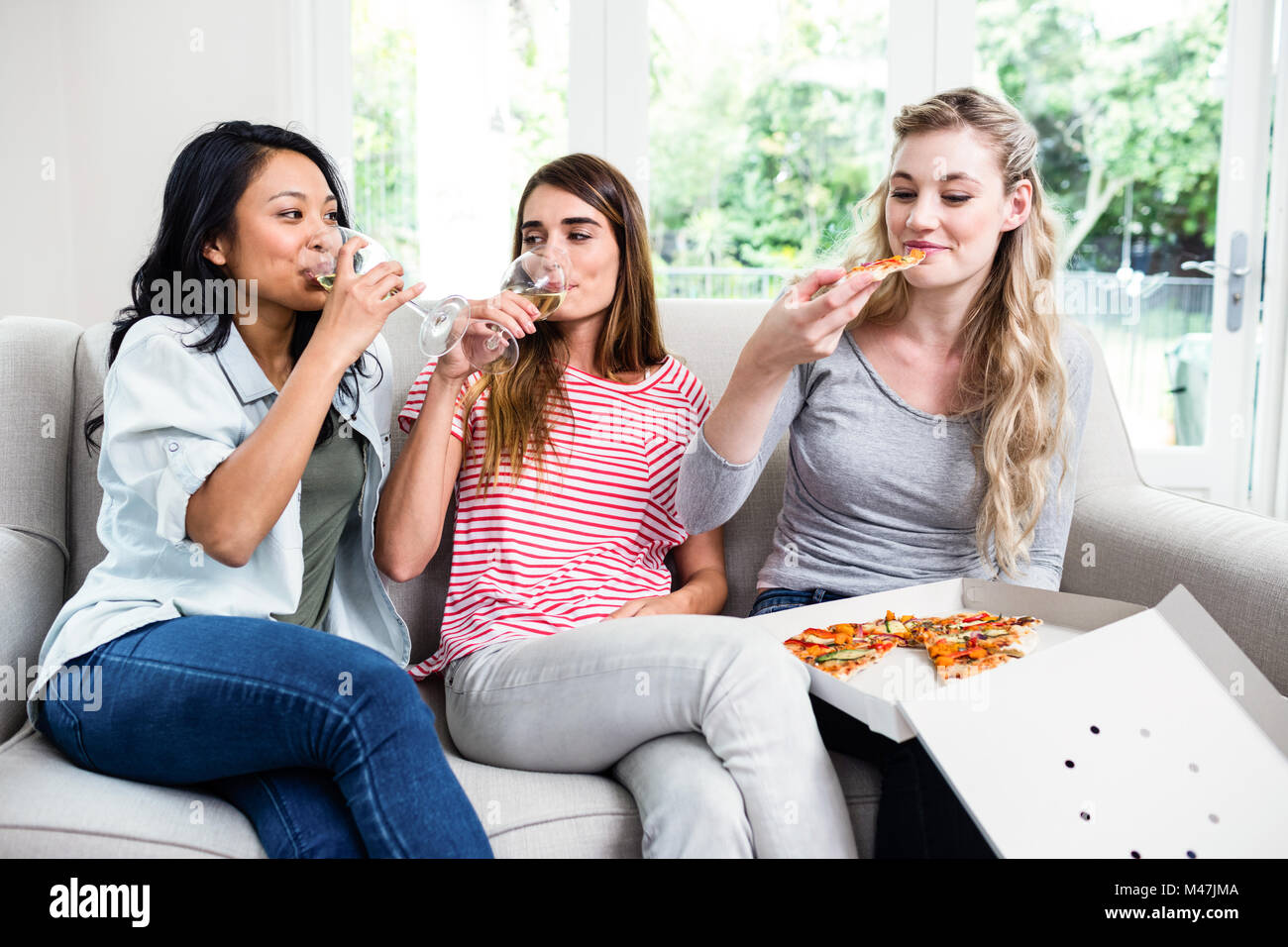 Freundinnen, die Snacks und Getränke zu Hause Stockfoto