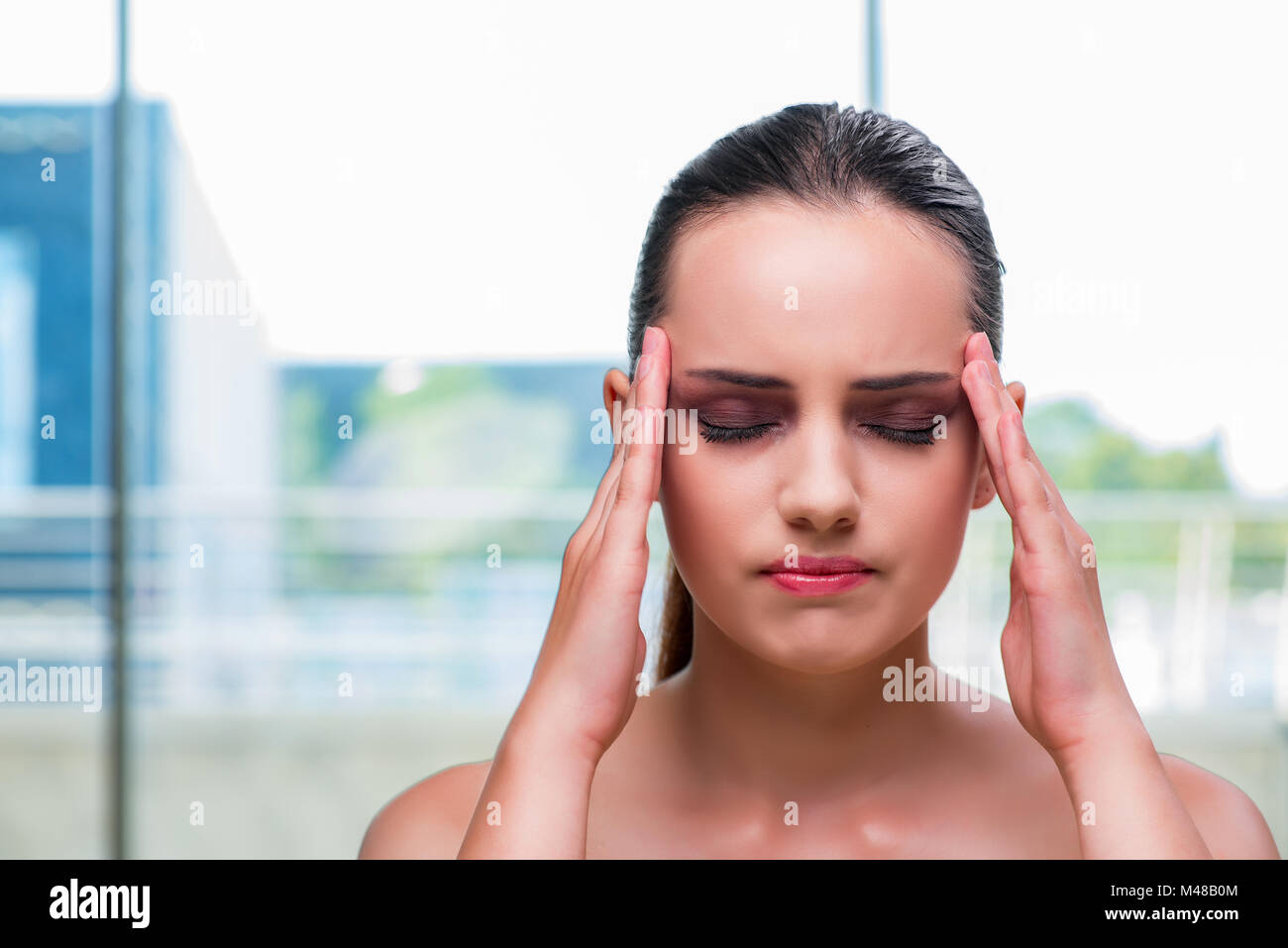 Junge Frau hält ihre Tempel mit Kopfschmerzen Stockfoto