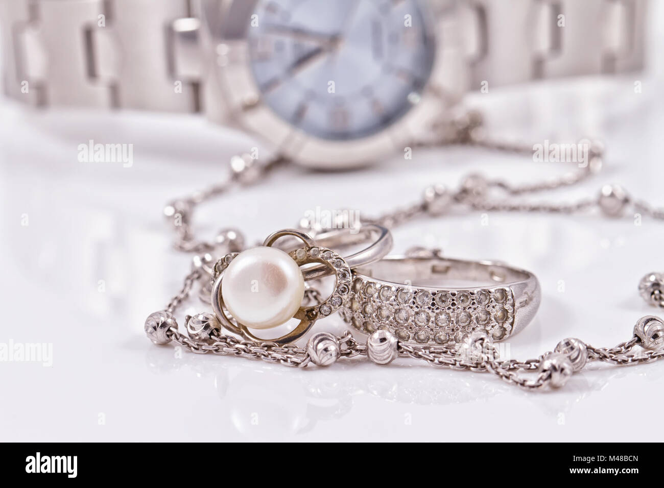 Silber Ring und Kette auf dem Hintergrund von Uhren Stockfoto