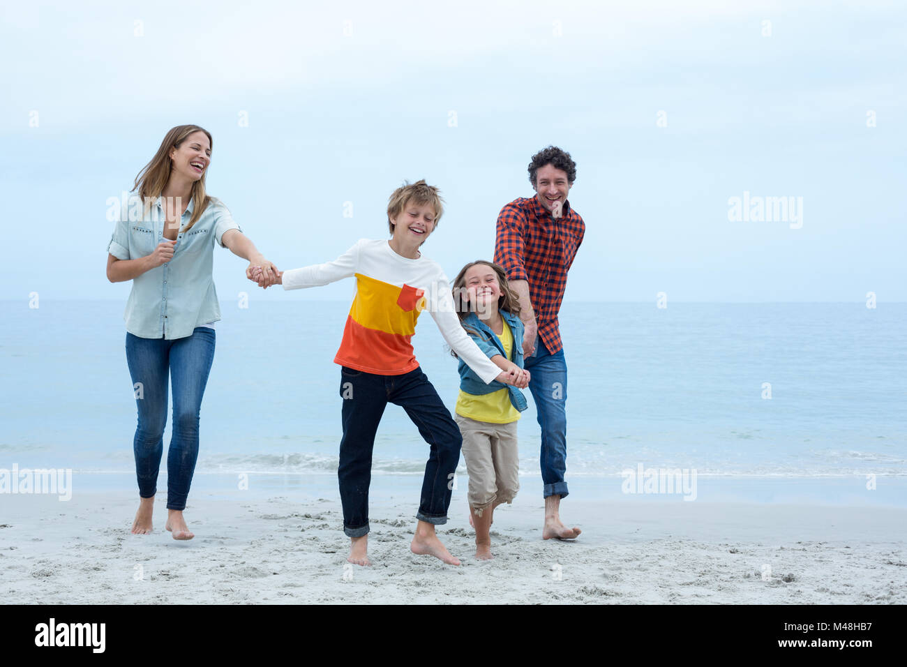Fröhliche Familie Hand in Hand während der Ausführung auf See Ufer Stockfoto