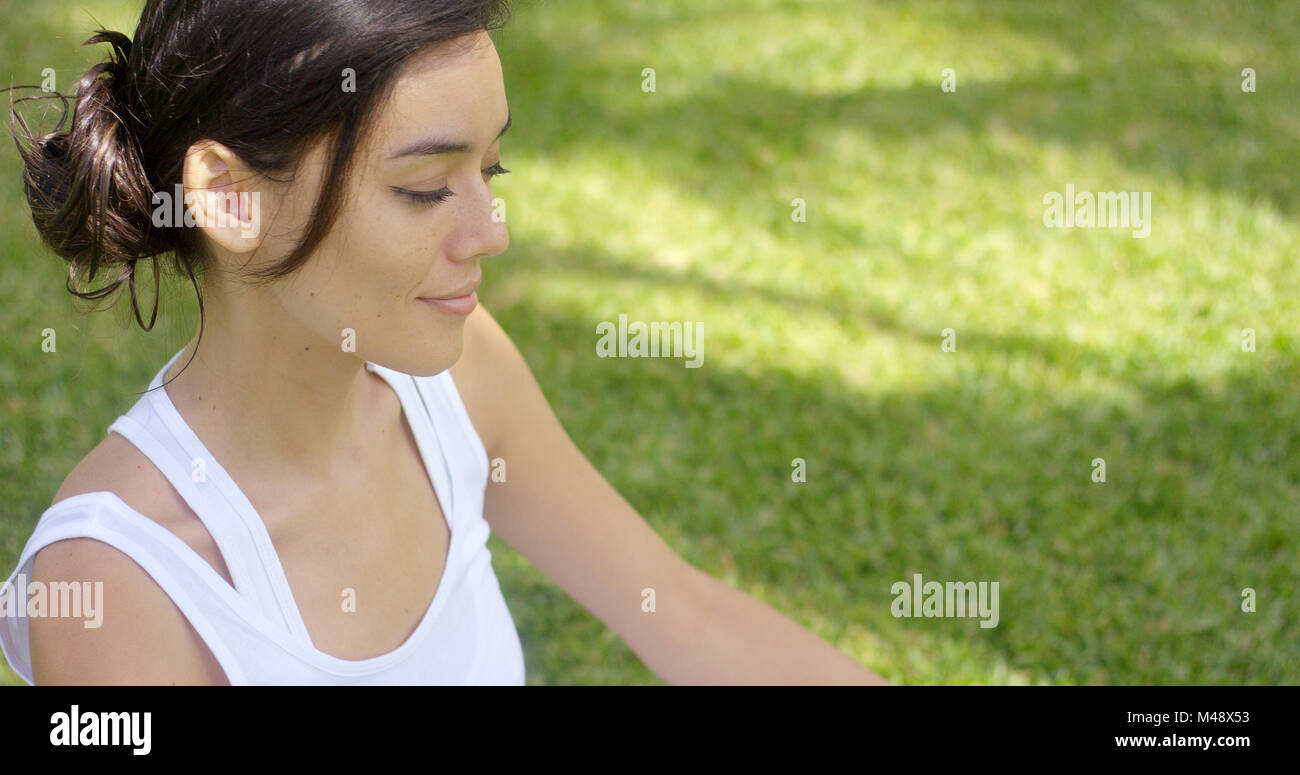 Ruhige junge Frau auf einem grünen Rasen zu meditieren Stockfoto