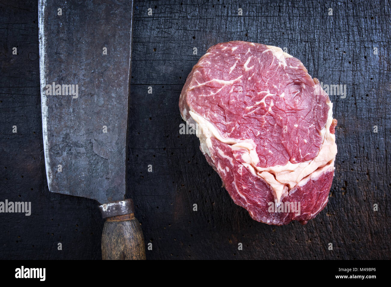 Trocken im Alter von Raw Rib Eye Steak mit Küche Cleaver Stockfoto