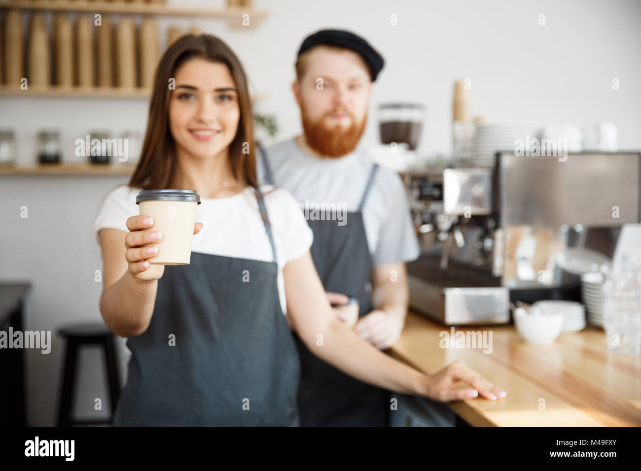 Kaffee Geschäftskonzept - Positive junger bärtiger Mann und schöne attraktive Lady barista Paar verlosen Tasse Kaffee nehmen an der modernen Coffee shop Custome Stockfoto