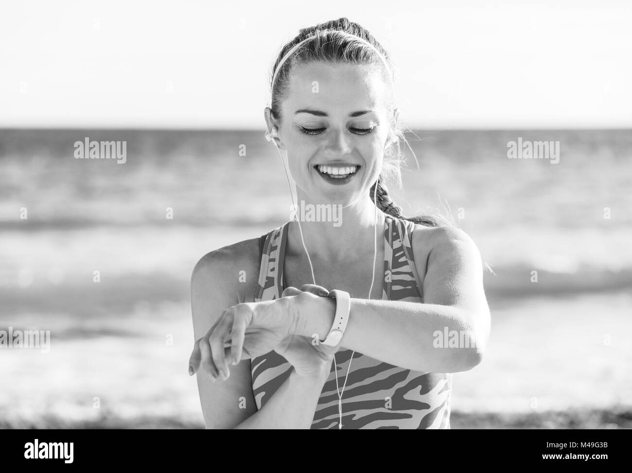 Erfrischende wilden Meer Seite Training. Glückliche junge gesunde Frau in Sports Gear, der am Ufer des Meeres bei Aktivität tracker suchen Stockfoto