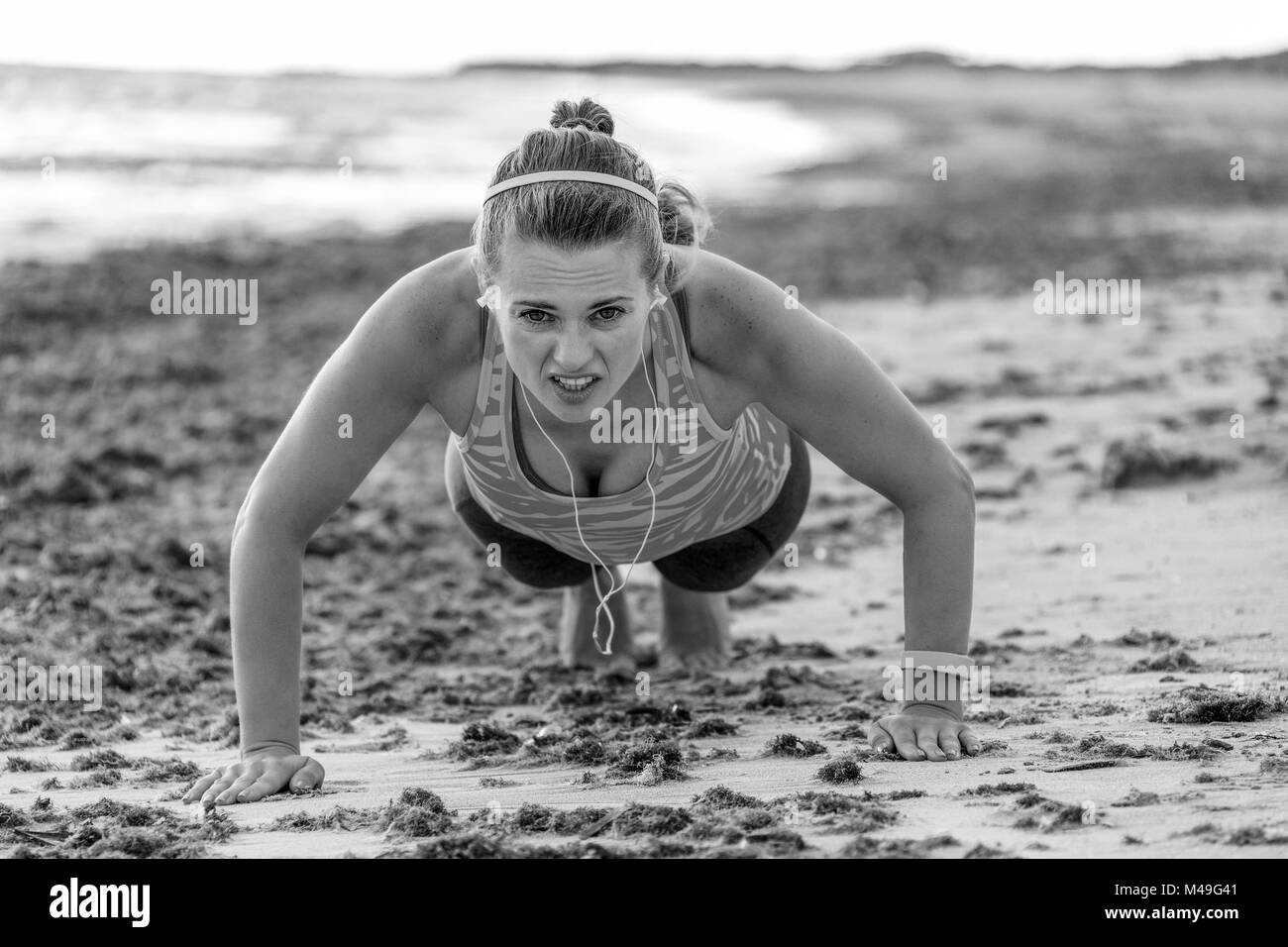 Erfrischende wilden Meer Seite Training. Junge passende Frau in Sports Gear, der am Ufer des Meeres pushups tun Stockfoto