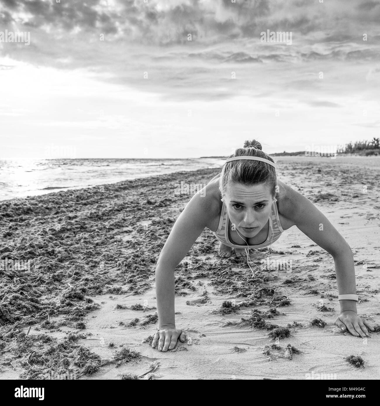 Erfrischende wilden Meer Seite Training. gesunde Frau im Sport Kleidung am Strand Liegestütze machen Stockfoto