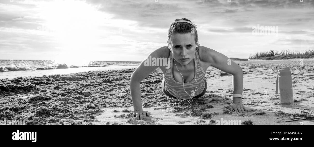 Erfrischende wilden Meer Seite Training. junge Sportlerin im Sport Kleidung, der am Ufer des Meeres pushups tun Stockfoto