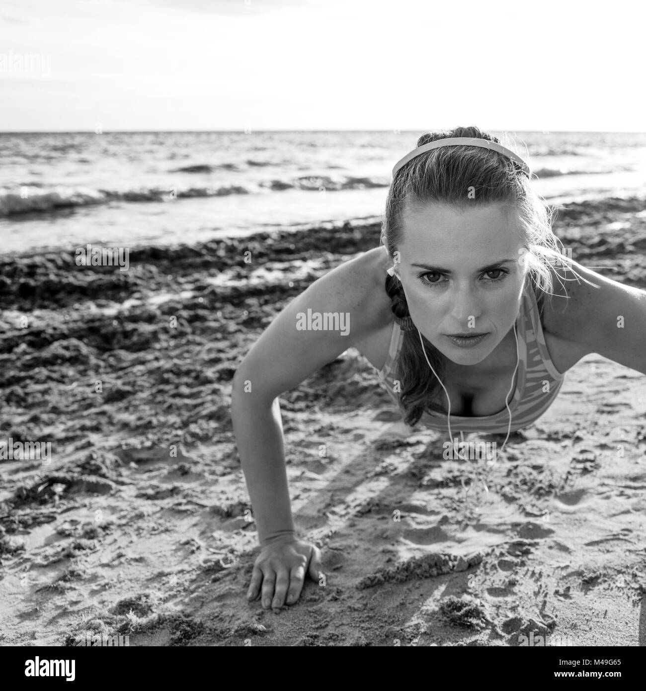 Erfrischende wilden Meer Seite Training. Aktiv fitness Frau in Sportswear am Strand Liegestütze machen Stockfoto