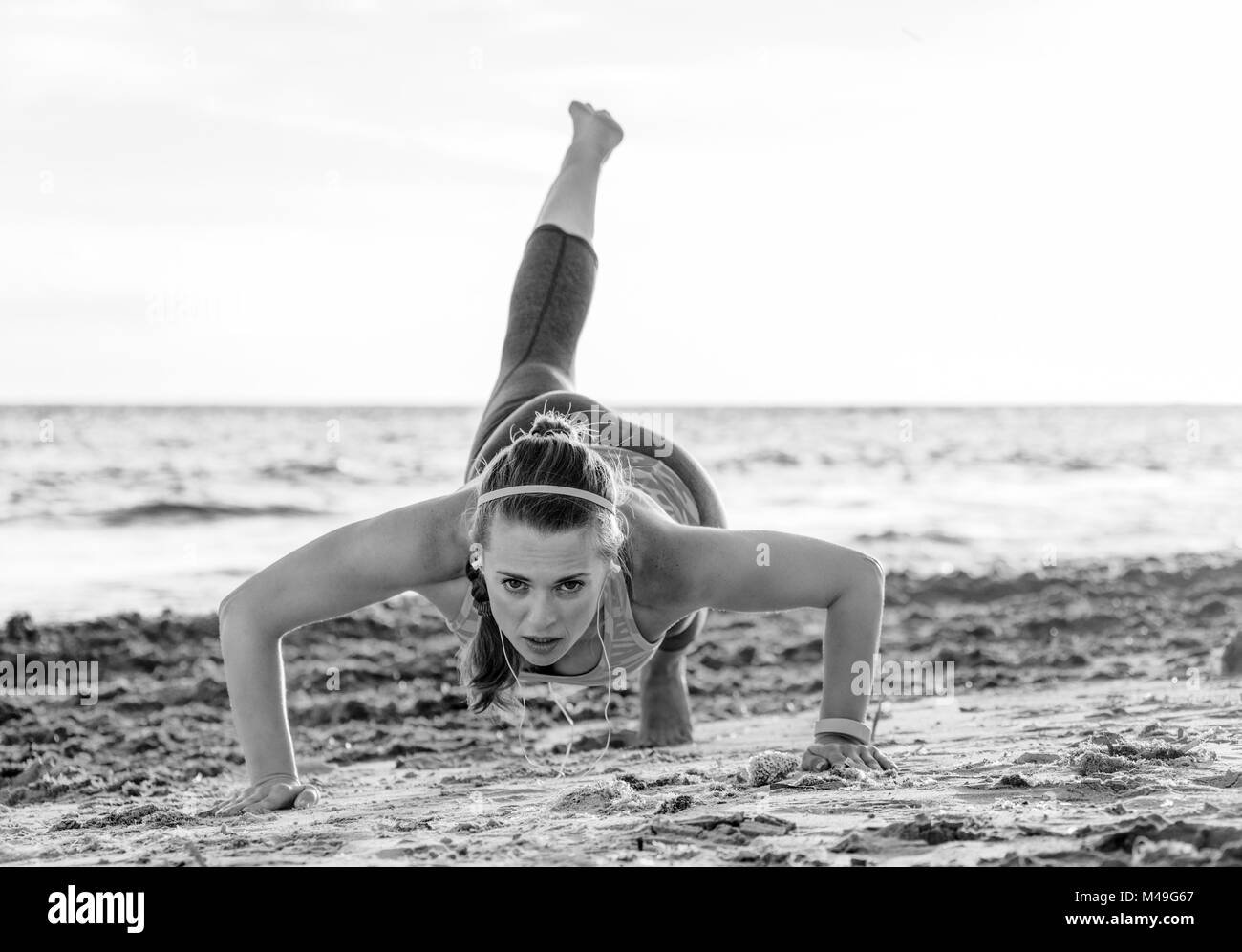 Erfrischende wilden Meer Seite Training. Aktiv fitness Frau in Sport Kleidung am Strand Liegestütze machen Stockfoto