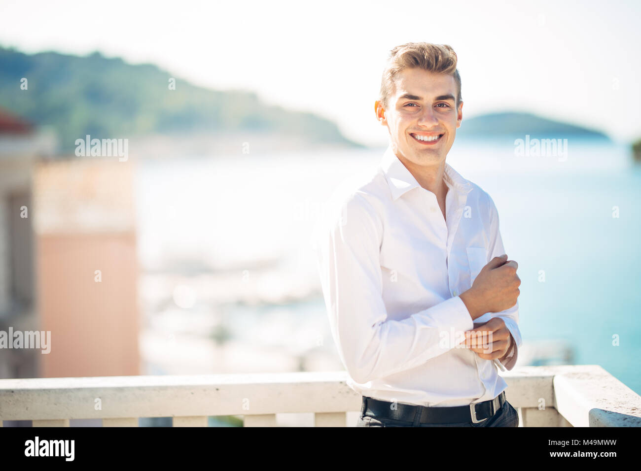 Junger stattlicher Mann mit Aufenthalt im Luxus Resort Hotel mit Panoramablick auf das Meer. lächelt Fröhlich business Mann an einem verdienten Urlaub in den Tropen. Summe Stockfoto