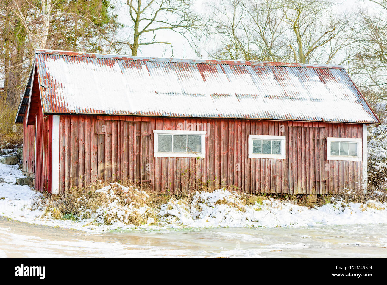 Alte und verwitterte rot Holz- Scheune oder Bauernhaus im Winter. Stockfoto