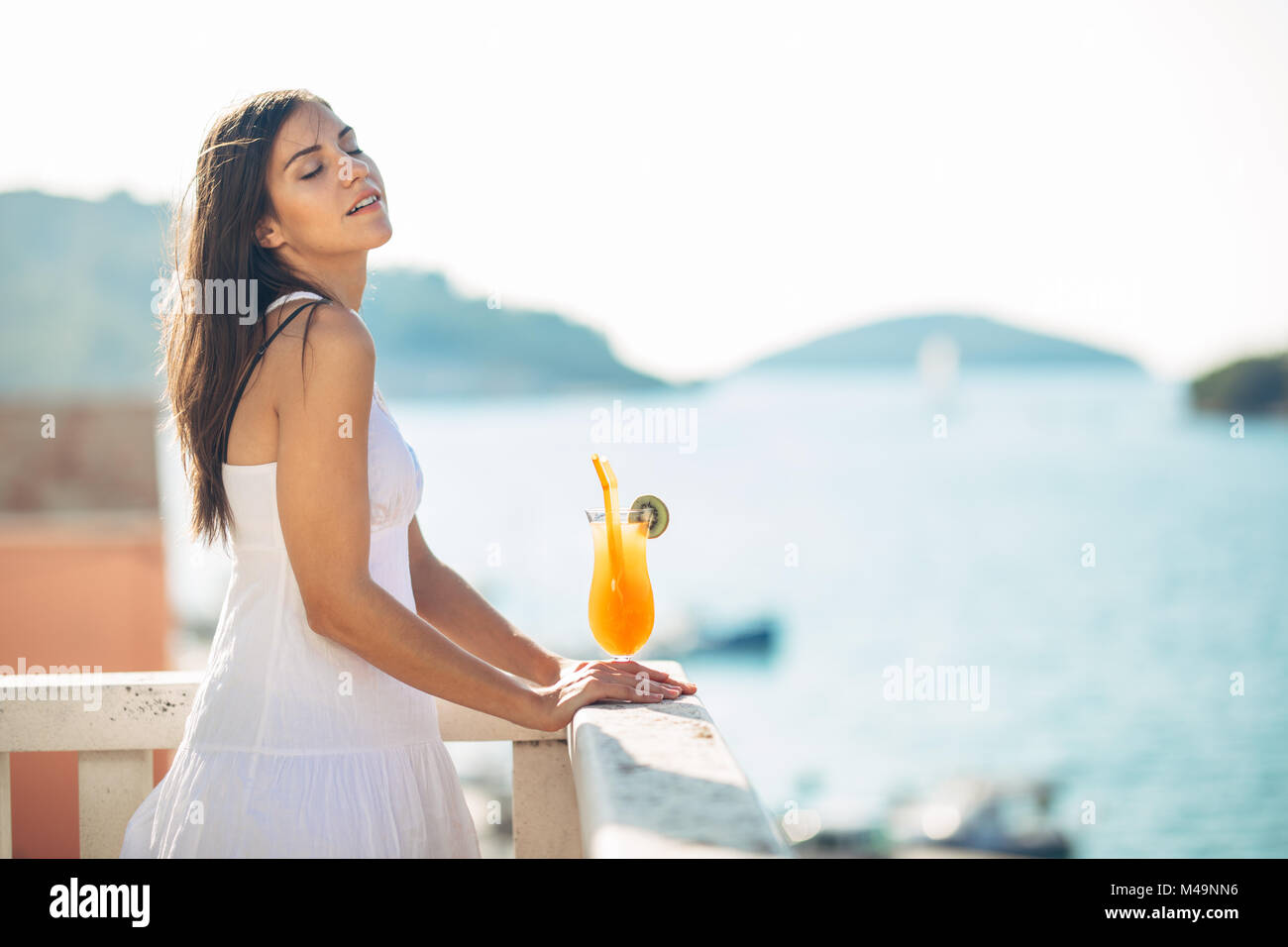 Junge Frau mit einem bunten Cocktail auf das Panorama Hotel Terrasse. kalten Cocktail Smoothie für den Sommer heisse Tage. Stockfoto