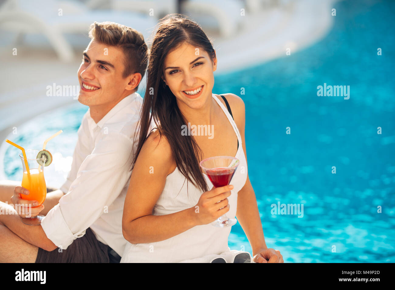 Junge fröhliche liebenden Paar Cocktails am Pool im Sommer Urlaub. romantischen Abend in Luxus Resort. Feiern Liebe, Engagement, Stockfoto