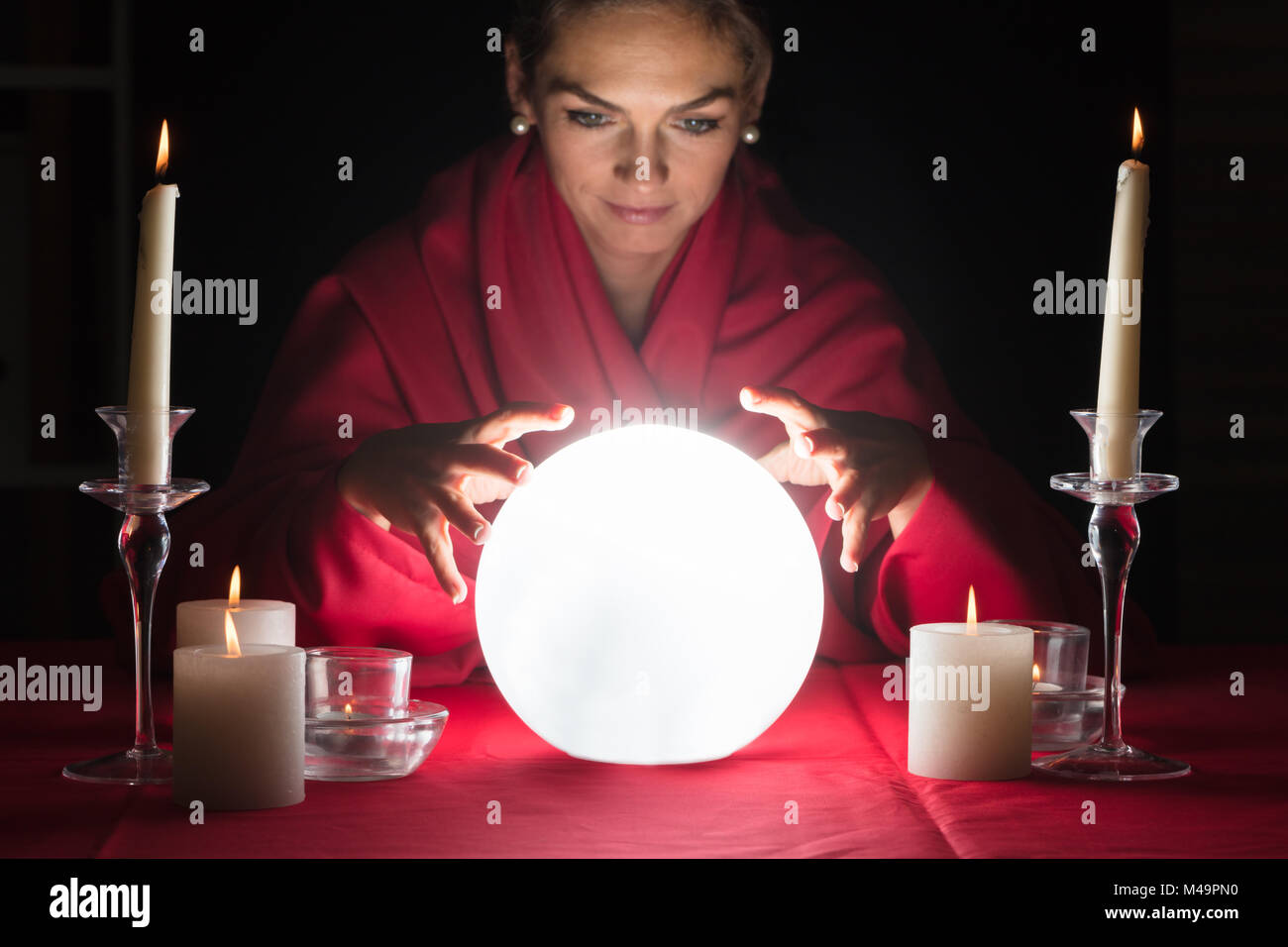 Schöne junge wahrsager halten sich an den Händen Um eine glühende Kugel Stockfoto