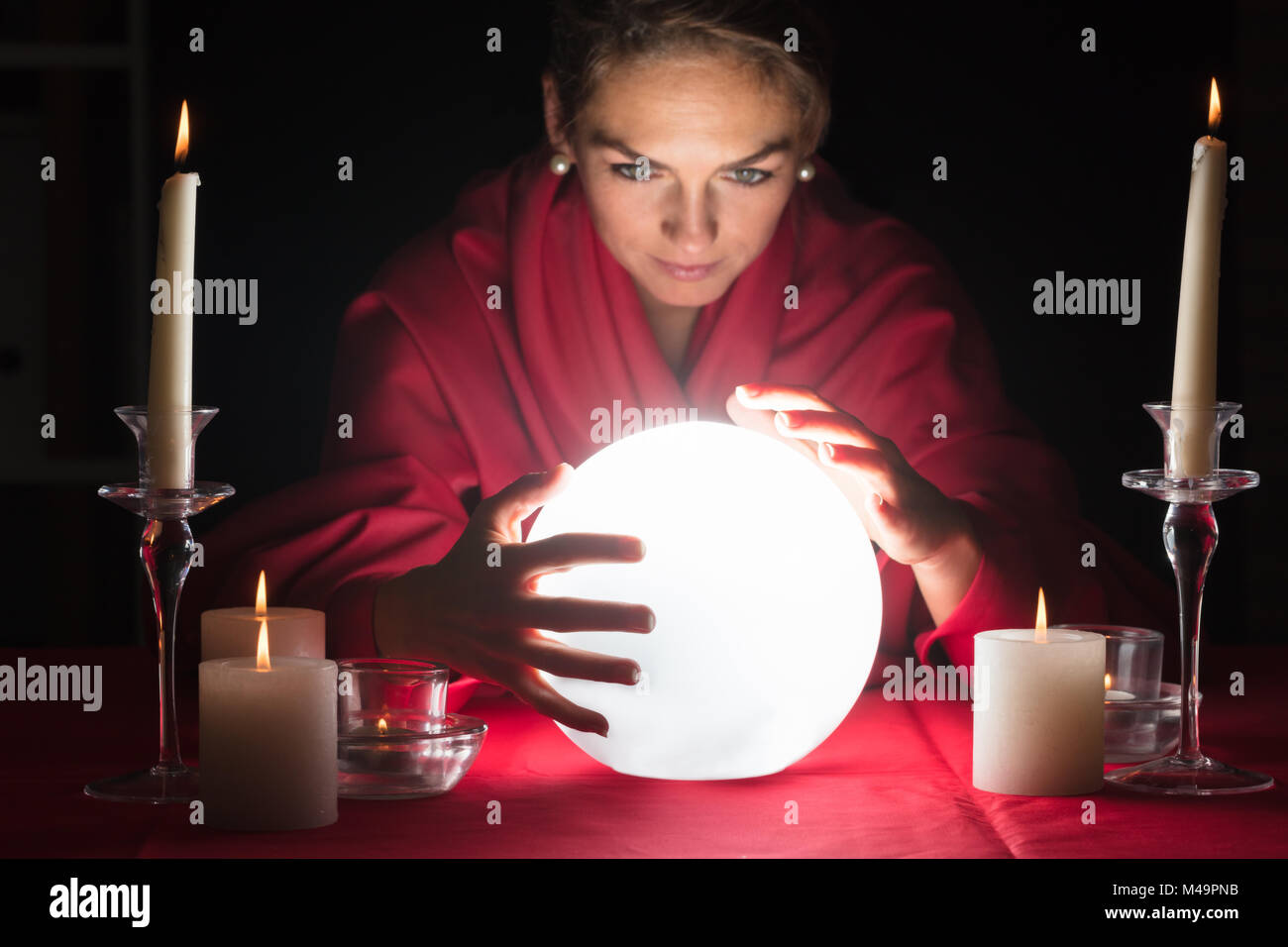 Schöne junge wahrsager halten sich an den Händen Um eine glühende Kugel Stockfoto