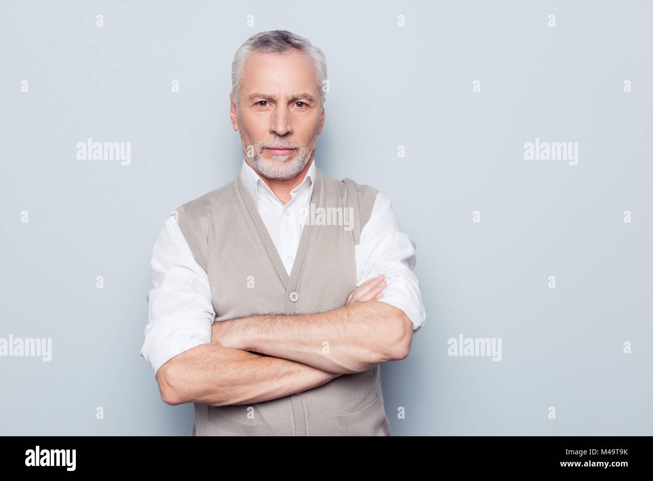 Menschen individuellen Lifestyle Konzept. Portrait von Viril ernst gesinnten Selbstbewusst nachdenklich Opa mit gekreuzten Händen beige Strickweste isolat Stockfoto