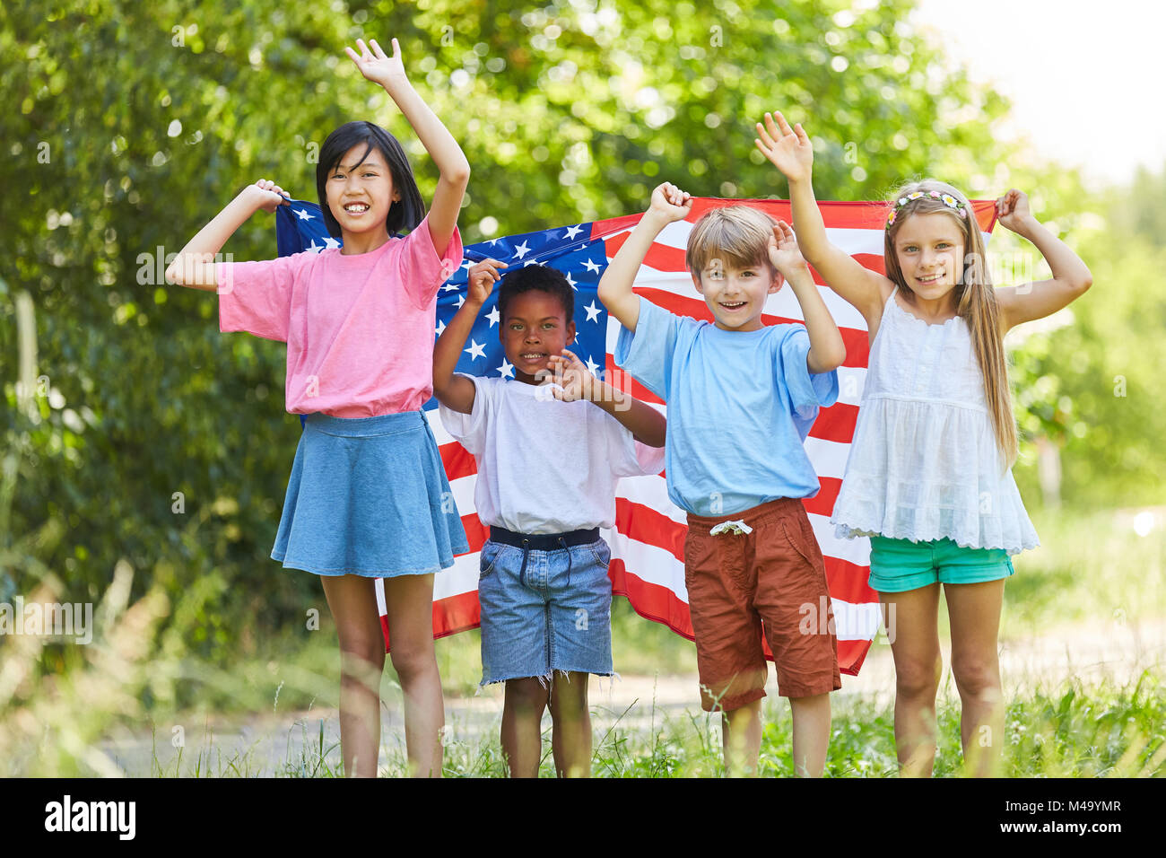 Multikulturelle Gruppe von Kindern mit der USA-Flagge ist fröhlich winkend Stockfoto