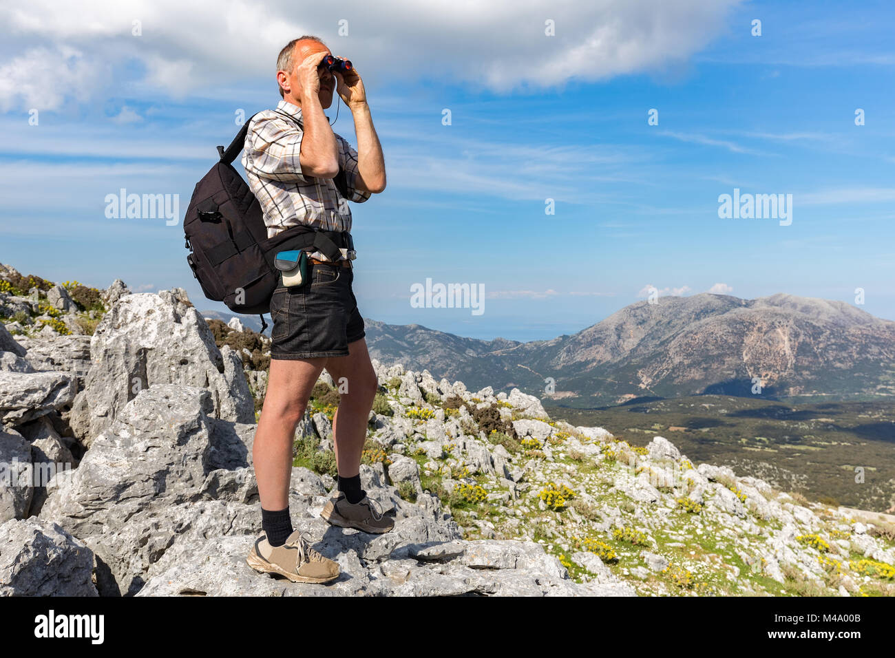 Europäischen Mann auf Felsen Blick durch ein Fernglas Stockfoto