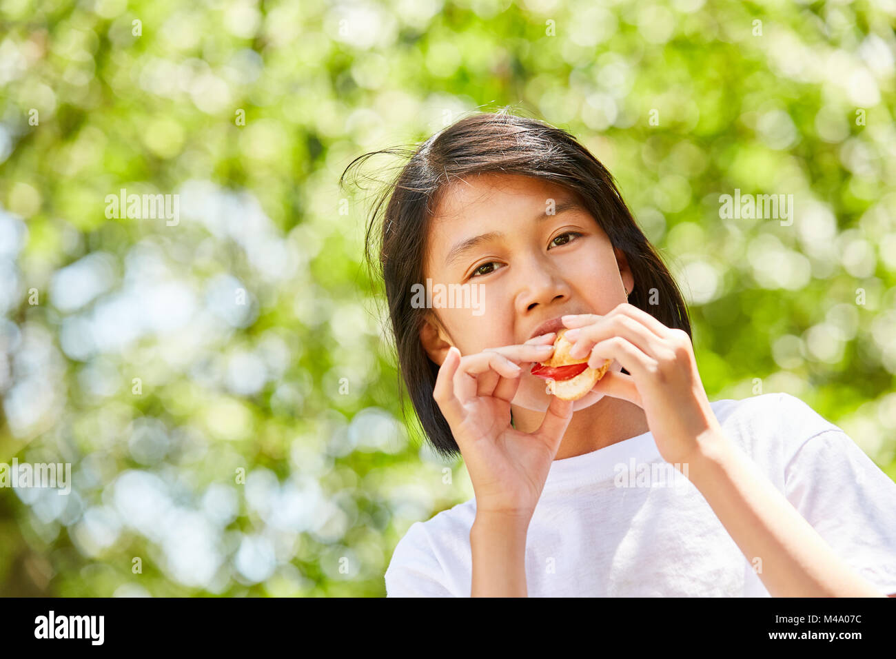 Asiatische Mädchen ist Essen ein Baguette als Pause Brot oder eine Party Snack Stockfoto