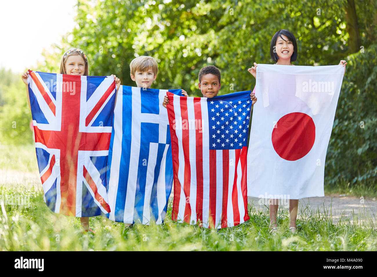 Multikulturelle Gruppe von Kindern hält die Fahnen von vier grossen Staaten Stockfoto