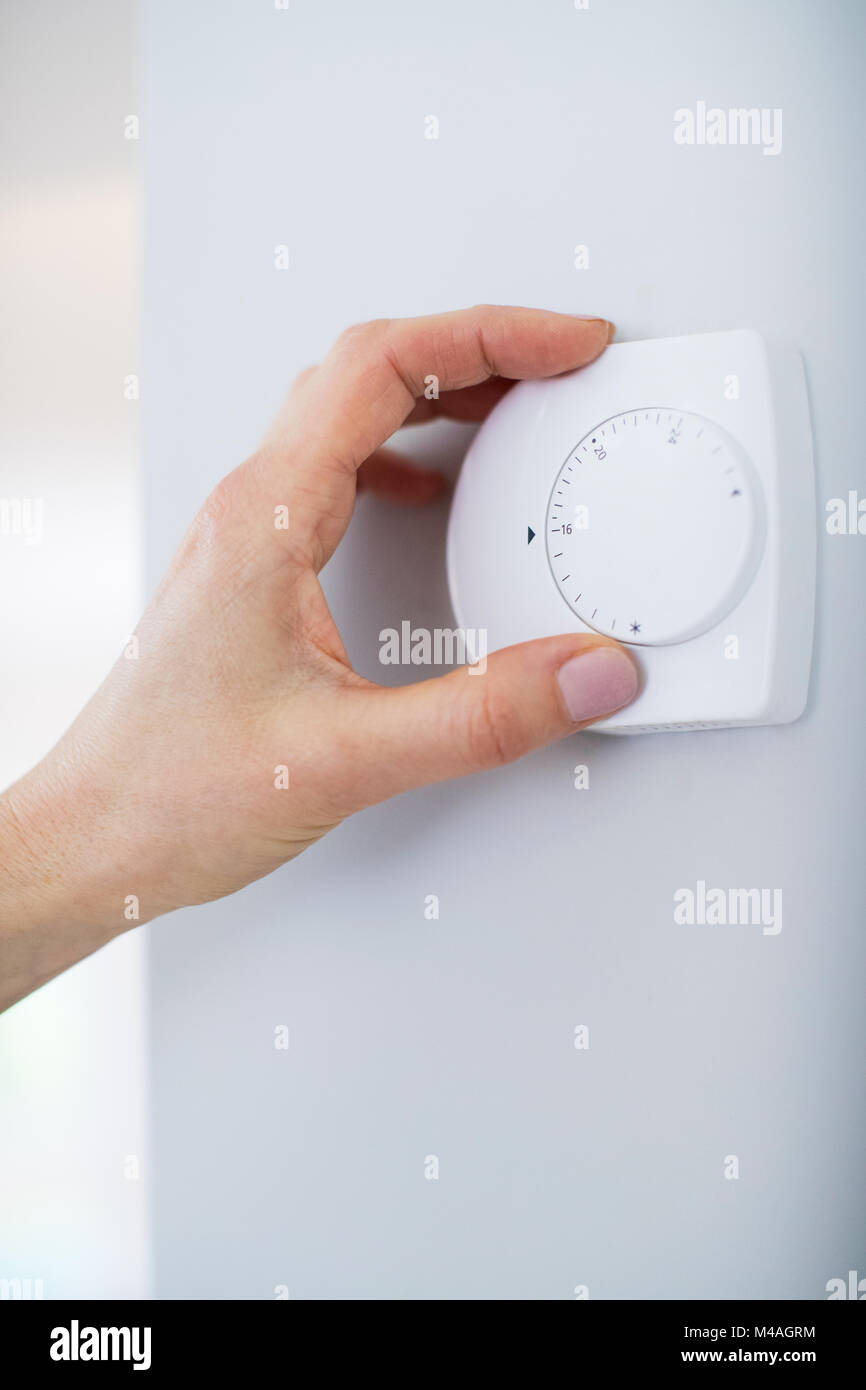 In der Nähe der weiblichen Hand auf zentrale Heizung Thermostat Stockfoto