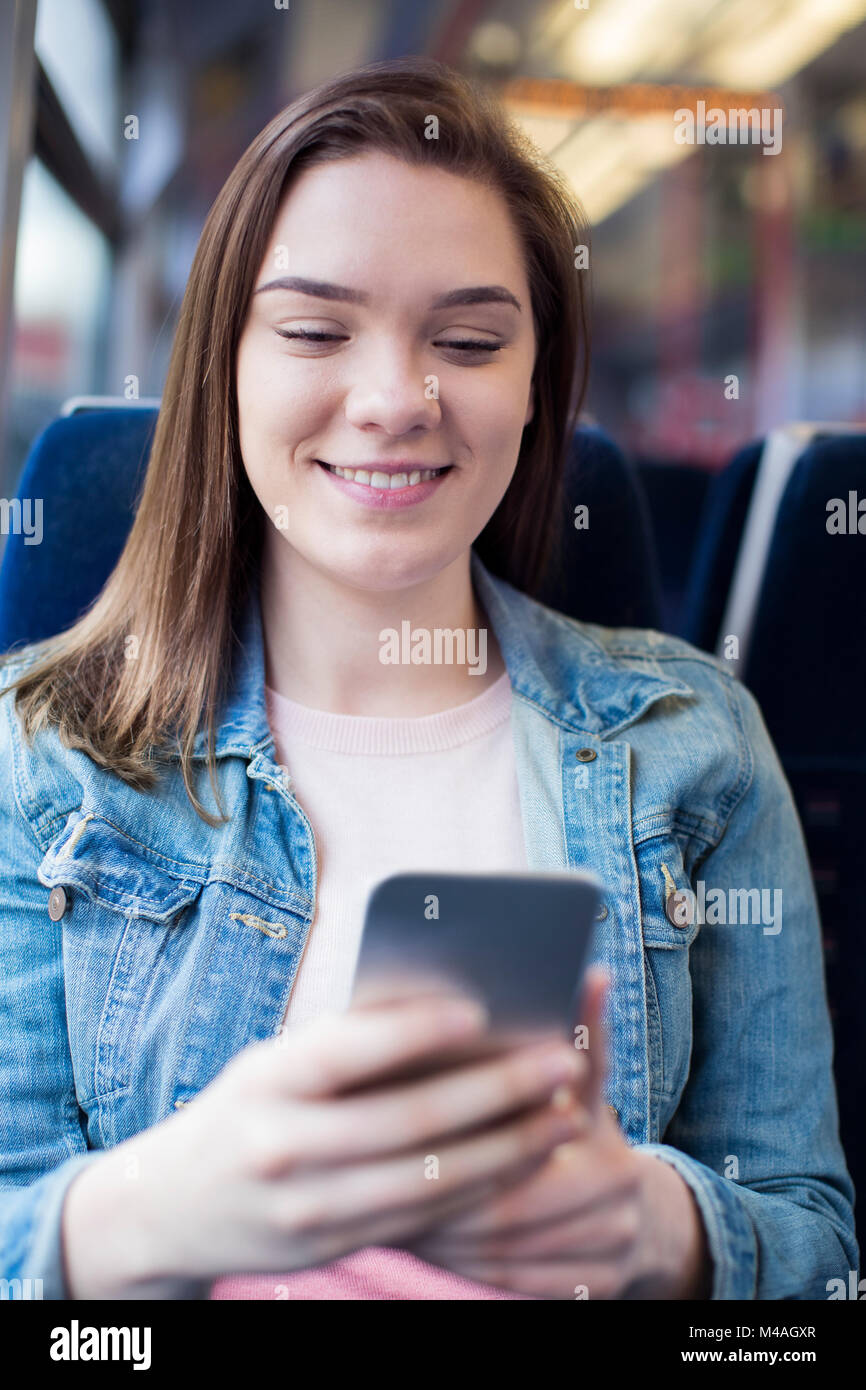 Junge Frau SMS auf Handy während der Fahrt Stockfoto