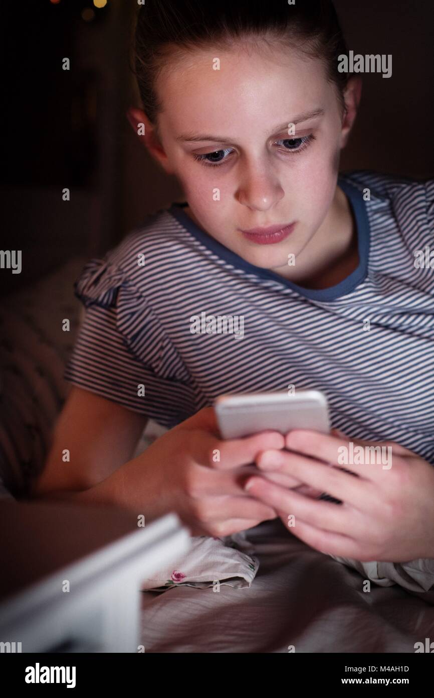 Junge Mädchen Opfer von Mobbing durch Sms liegen auf dem Bett in der Nacht Stockfoto