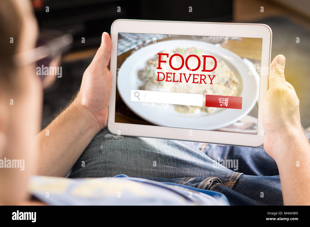 Essen Lieferung app auf Tablet. Mann mit Smart gerät zu Hause einen Auftrag vom Restaurant online zu machen. Imaginäre Anwendung, Website und Internet store Stockfoto