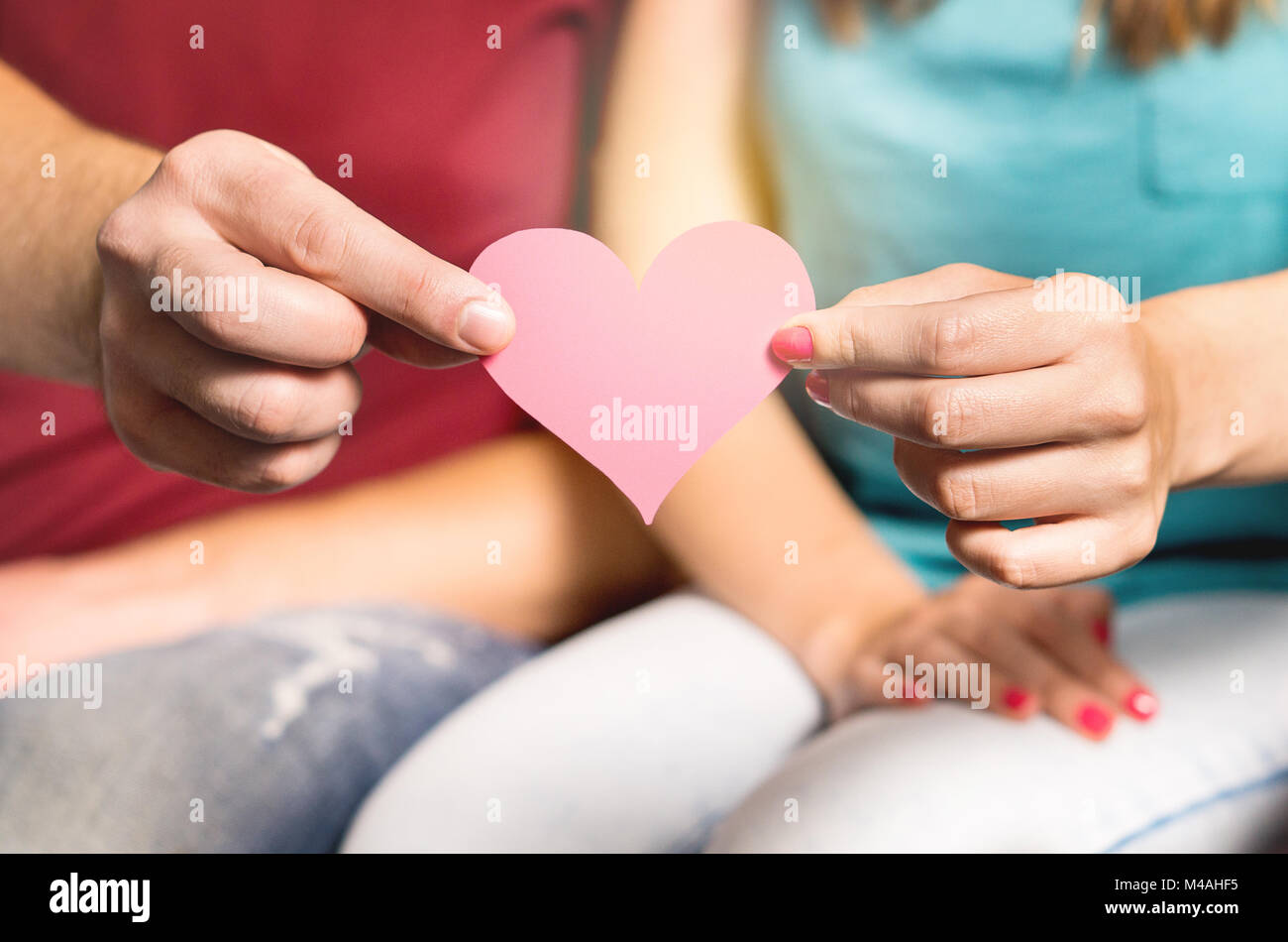Glückliches Paar gleichen Herz aus Papier zusammenhalten. Der Mann und die Frau mit Pappe Liebe Symbol in der Hand. Valentinstag oder Geburtstag. Stockfoto