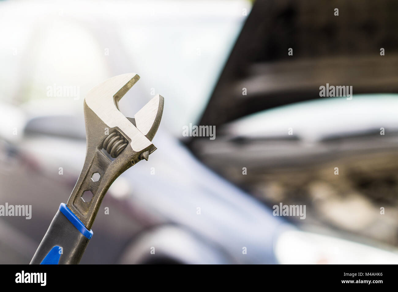 Auto Reparatur, Wartung und Inspektion Konzept. Schraubenschlüssel und ein Auto mit unter der Haube und Motor. Selektiven Fokus auf Festsetzung Werkzeug. Stockfoto