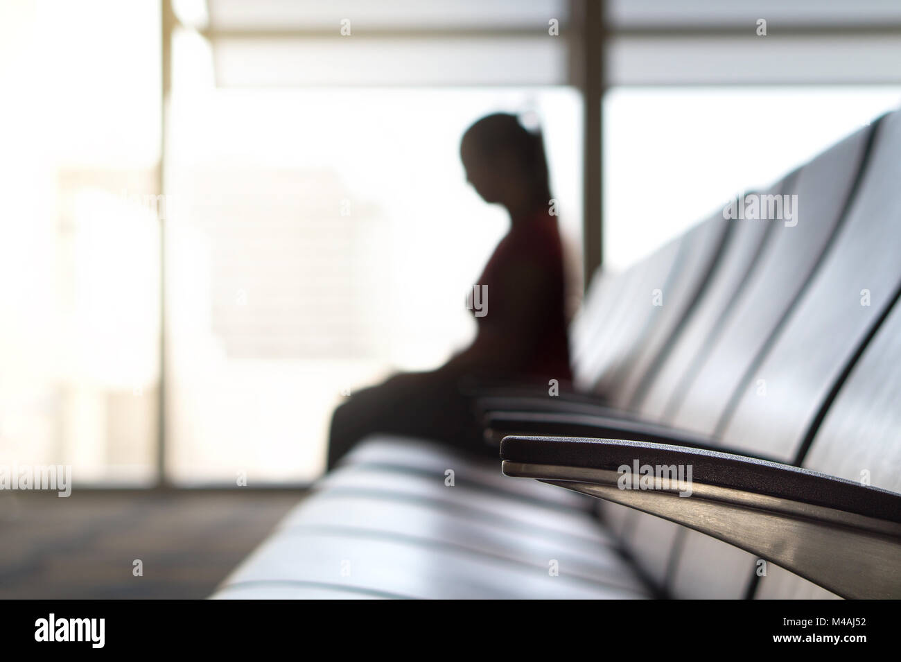 Person im Warteraum am Tor vor dem Einsteigen und Flug sitzen. Silhouette Frau in der Abflughalle am Flughafen. Reisen, Urlaub und Transport Stockfoto
