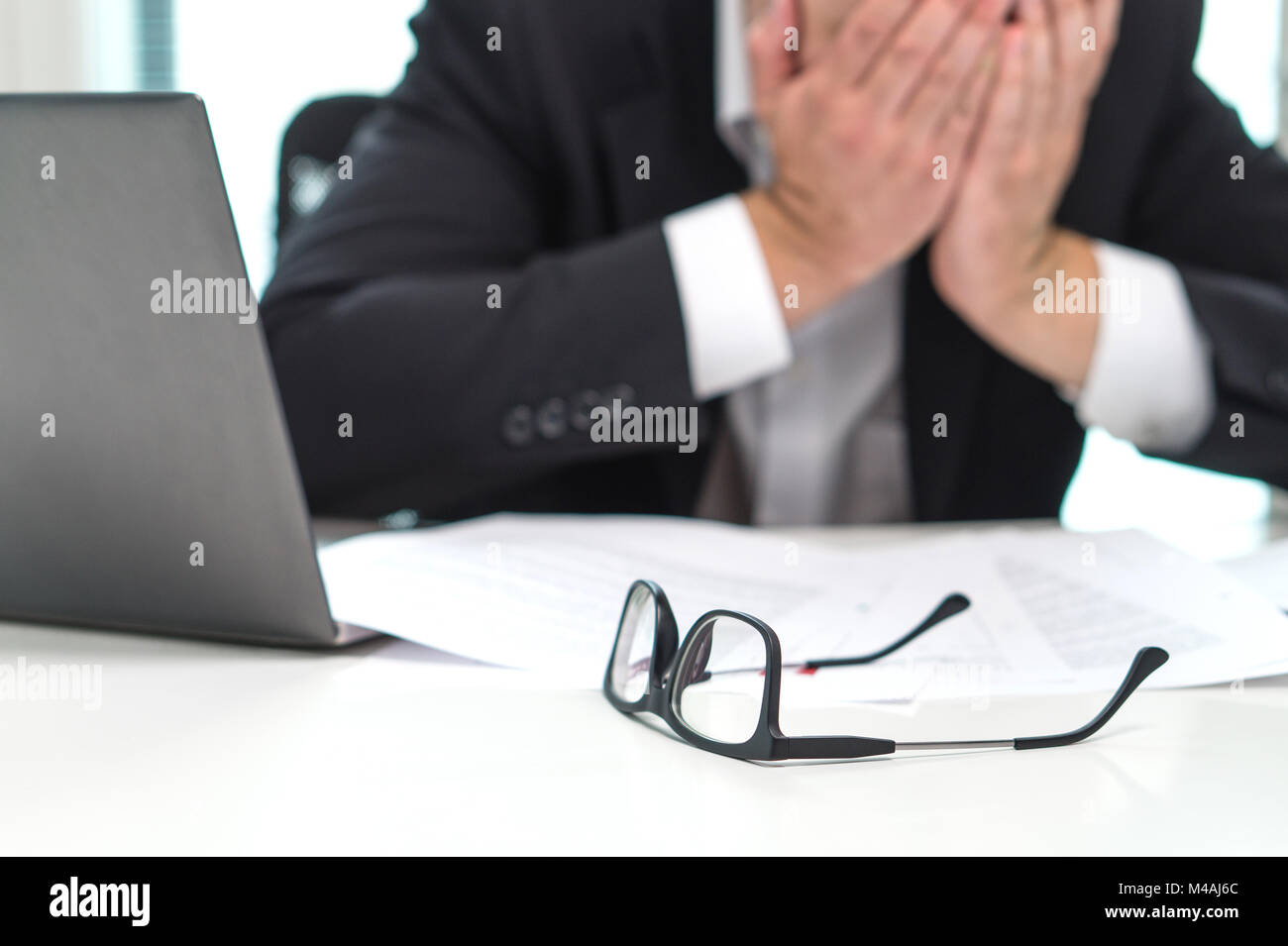 Geschäftsmann mit Gesicht mit den Händen im Büro betont. Im Laufe der Zeit arbeiten oder zu viel. Problem mit fehlerhaften oder Verwechslungen mit der Krise. Stockfoto