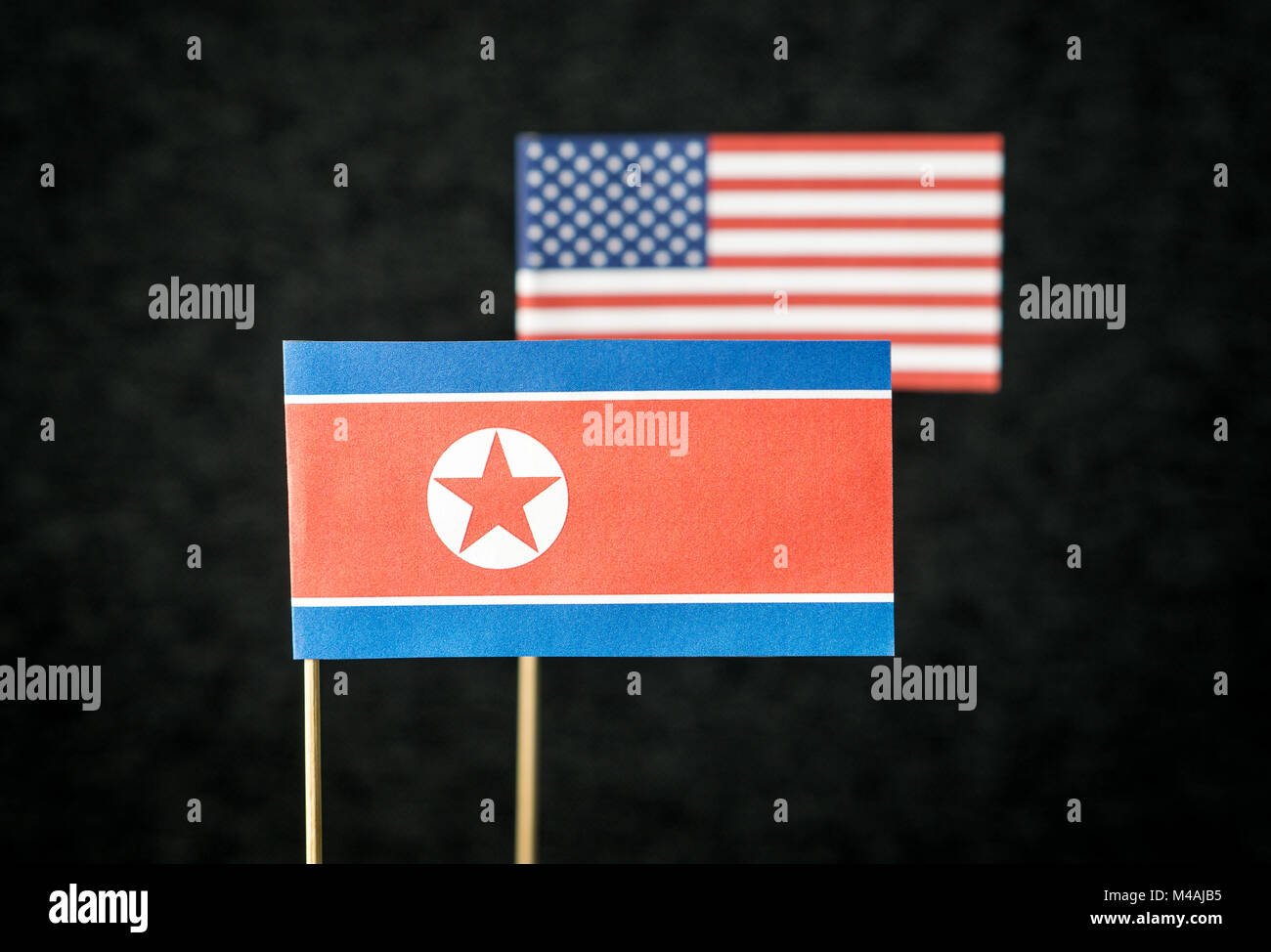 Die Fahne von Nordkorea und die Vereinigten Staaten von Amerika (USA) aus Papier auf Holz stick gegen den dunklen Hintergrund. Stockfoto