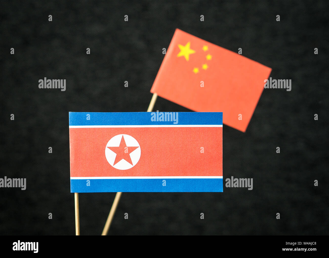 Die Fahne von Nordkorea und China aus Papier auf Holz stick gegen den dunklen Hintergrund. Stockfoto