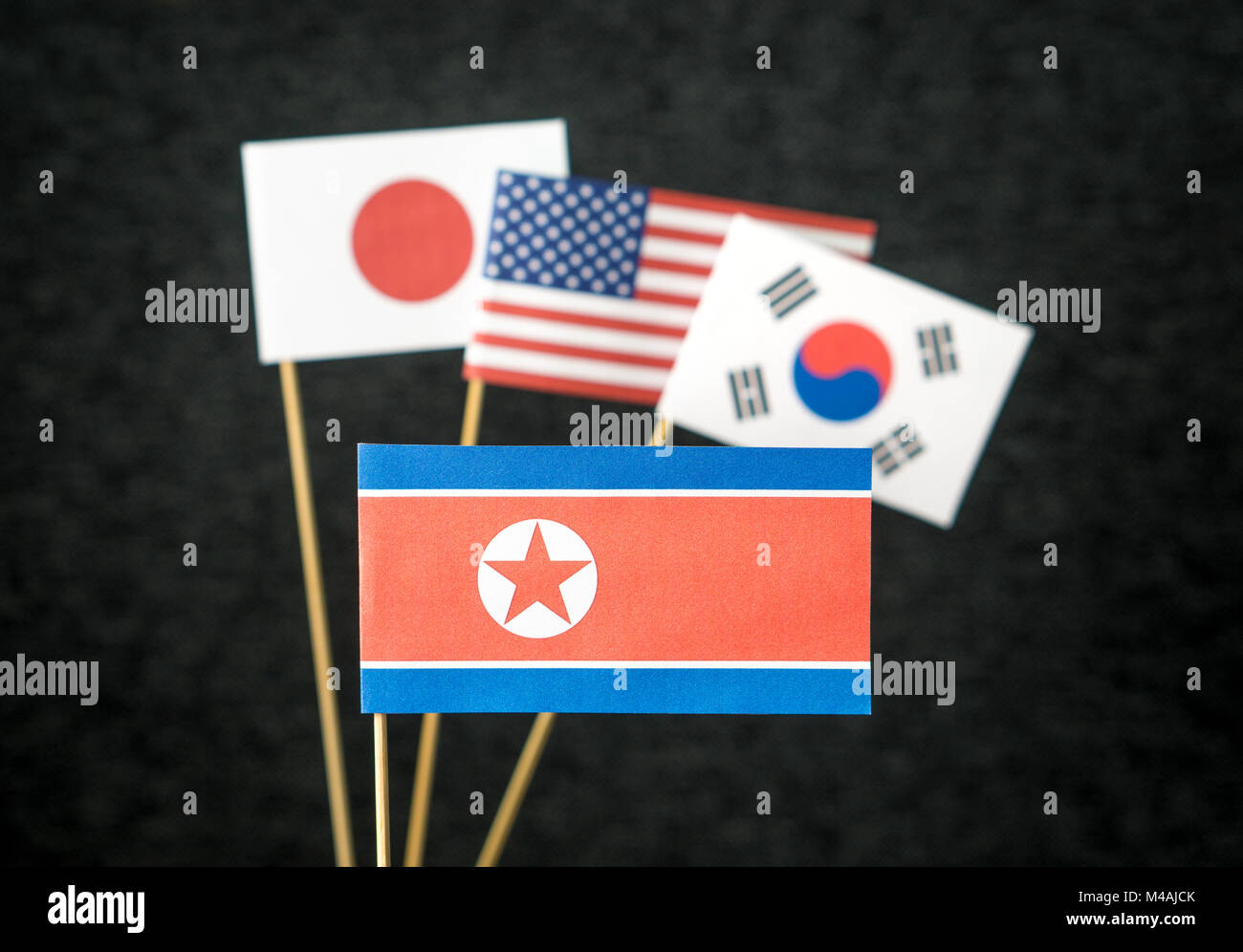 Die Fahne von Nordkorea, Vereinigte Staaten von Amerika (USA), Südkorea und Japan aus Papier auf Holz stick gegen den dunklen Hintergrund. Stockfoto
