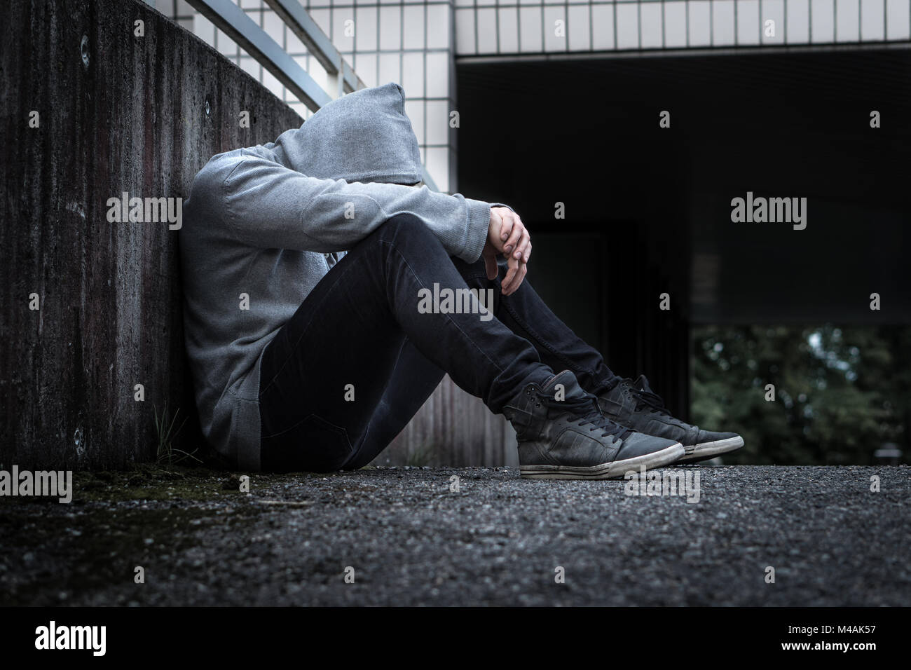 Depressionen, soziale Isolation, Einsamkeit, psychische Gesundheit und Diskriminierung Konzept. Traurig, einsam, depressiv und unglücklich, Mann. Vermummte Person sitzen. Stockfoto