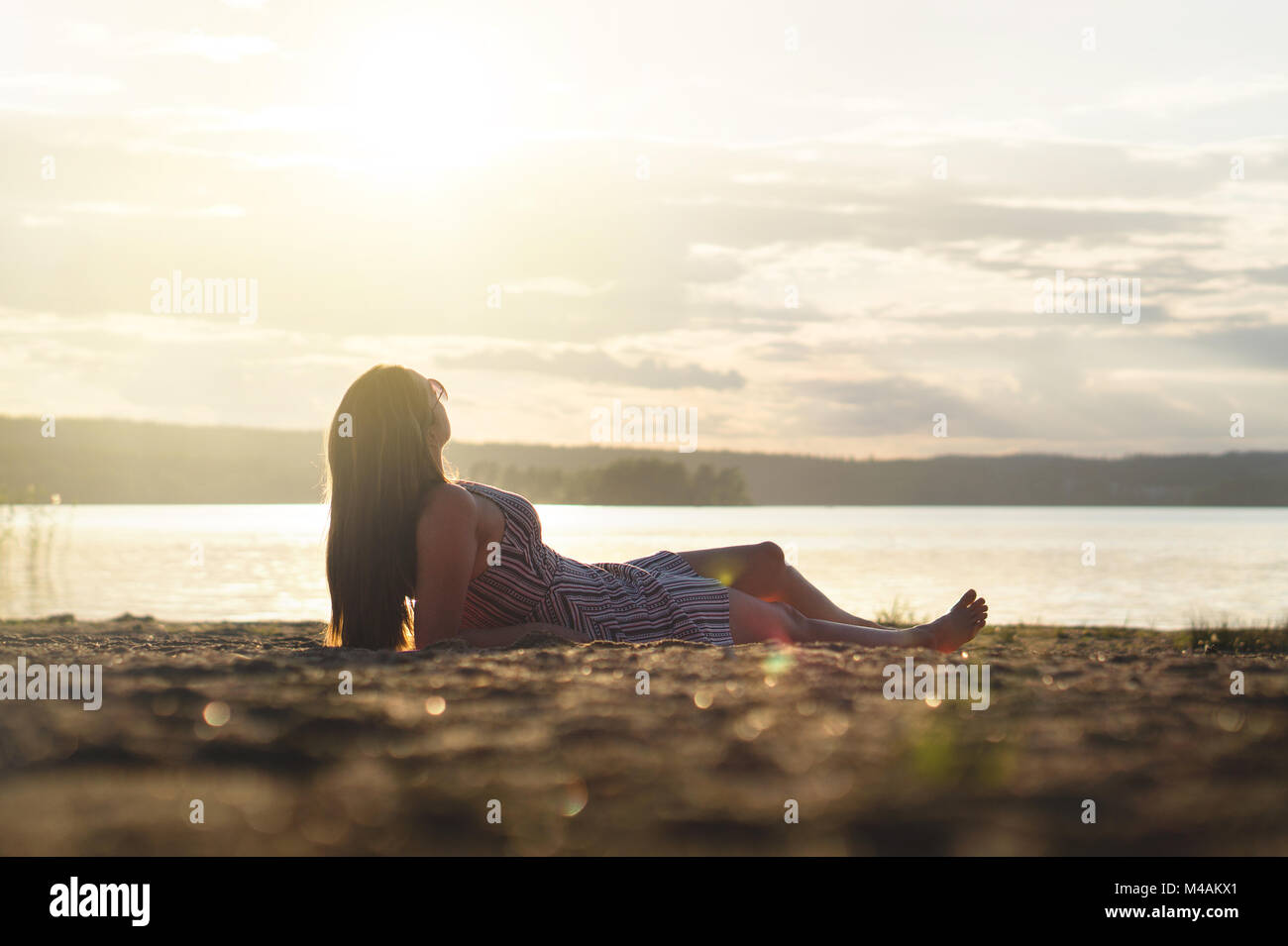 Frau entspannen Sie sich und legte sich in den Sonnenuntergang am Strand. Sorglos und glücklich Lifestyle. Stockfoto