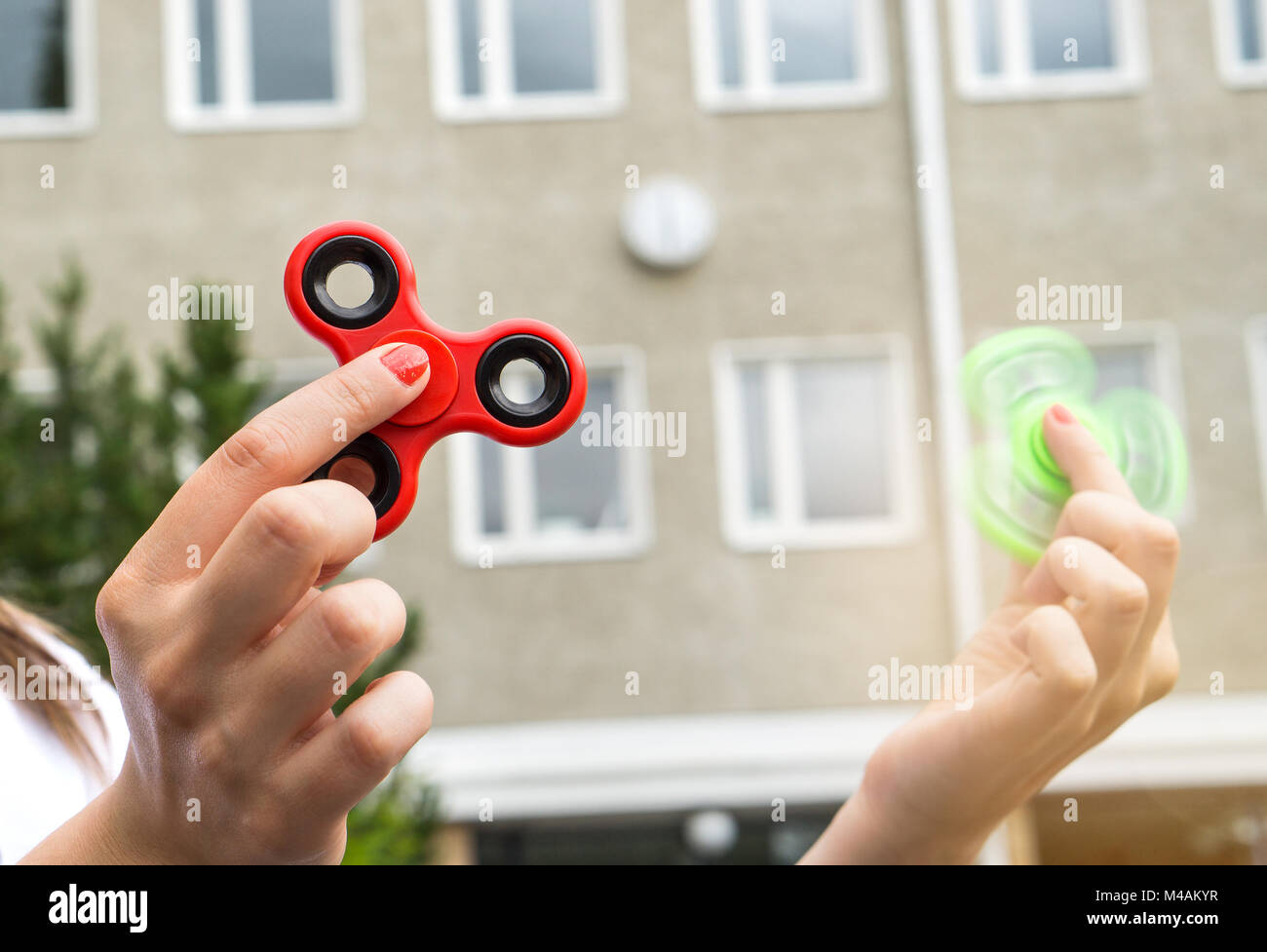 Teenage Mädchen spielen mit zwei zappeln Spinner in der Pause oder Kabelbruch im Schulhof. Stockfoto