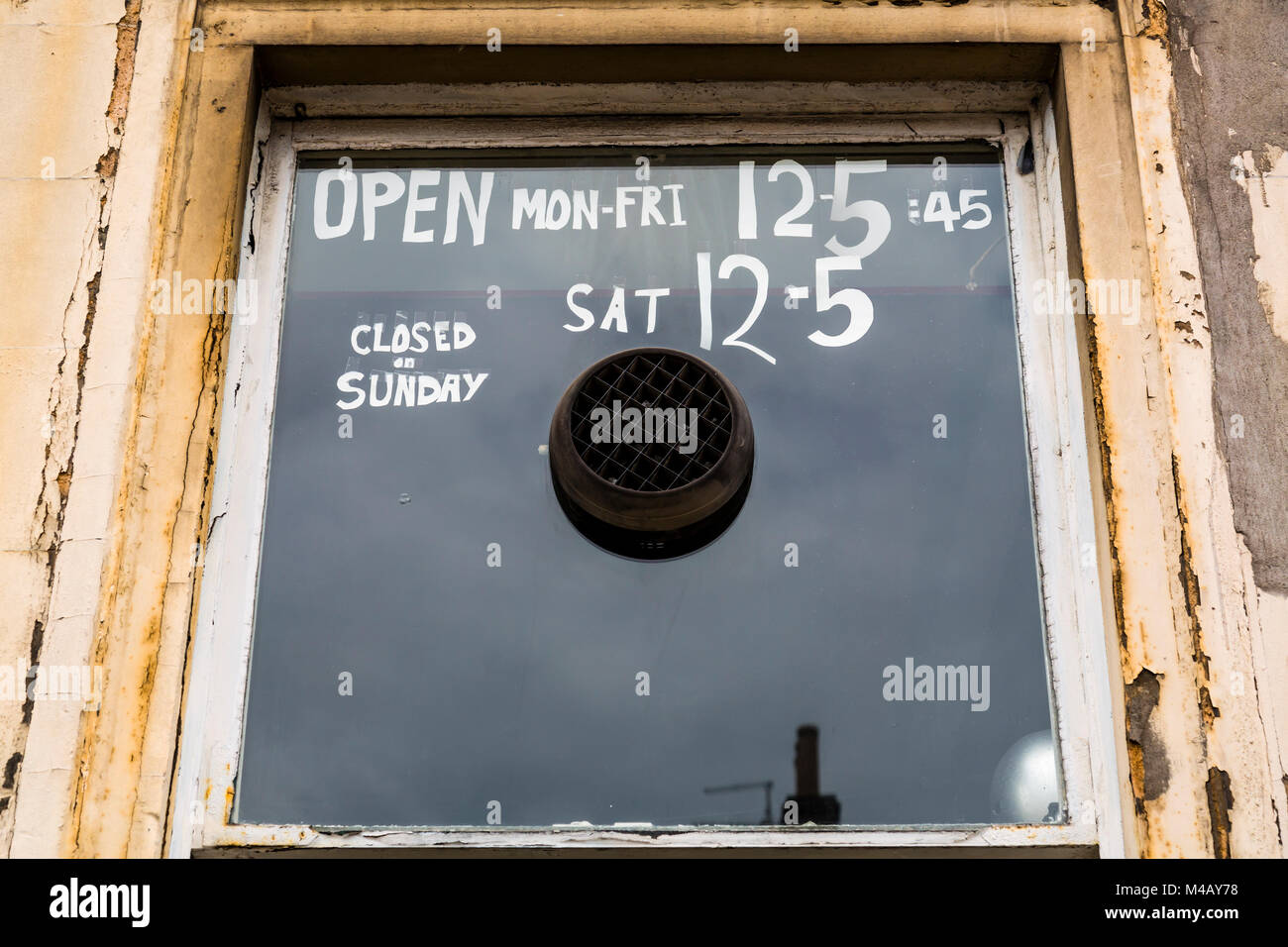 Öffnungszeiten an einem alten Schaufenster Stockfoto