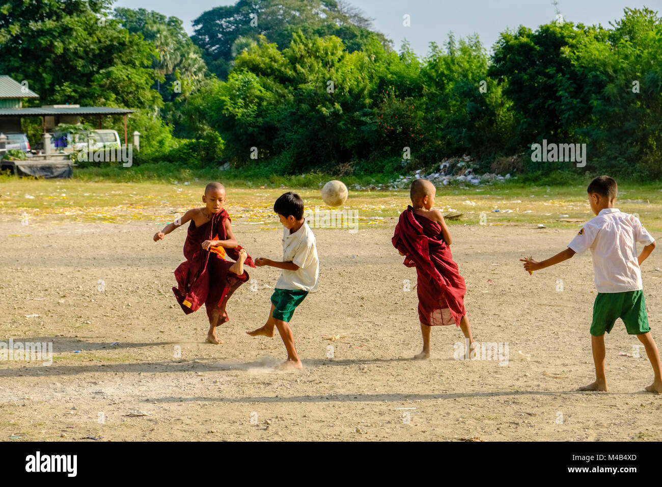 Junge Mönche sind Fußball spielen mit den lokalen Jungen Stockfoto