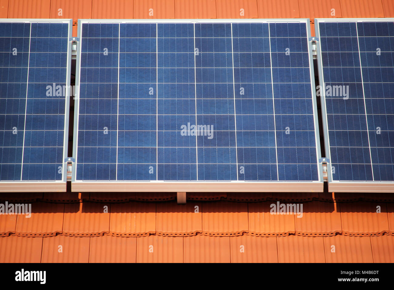 Sonnenkollektoren auf dem roten Dach eines privaten Hauses Strom produzieren, industriellen Hintergrund Stockfoto